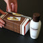 Tabac Original Geschenkschuber wird um das Produkt gelegt.